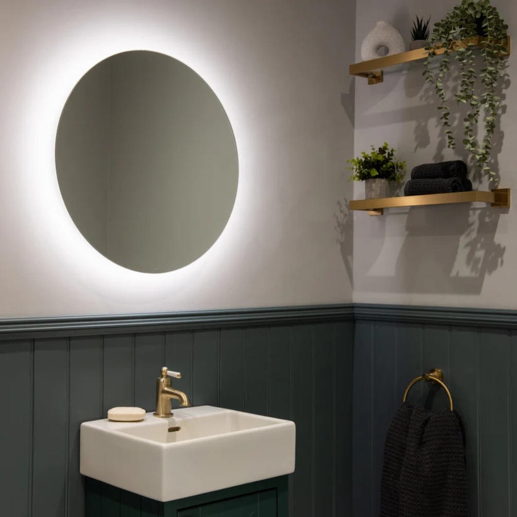 Lifestyle image of the Sensio Lustro Round 600mm Rechargeable Backlit LED Mirror mounted on a bathroom wall, above a vanity unit & basin